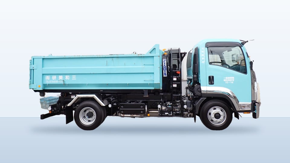 水色の脱着コンテナ車。荷台に、水色のコンテナを載せている。
