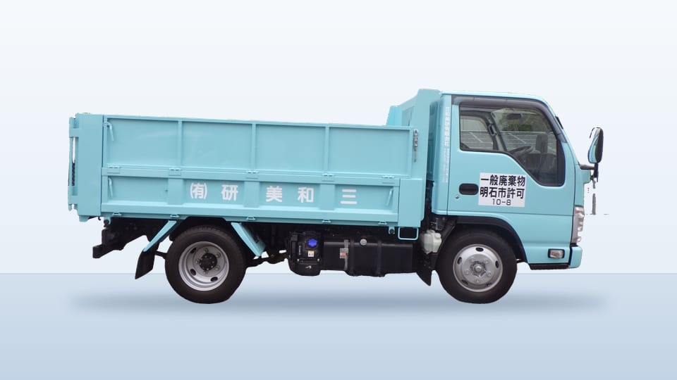 水色のダンプ車の側面。荷台に「三和美研」の社名が入っている。