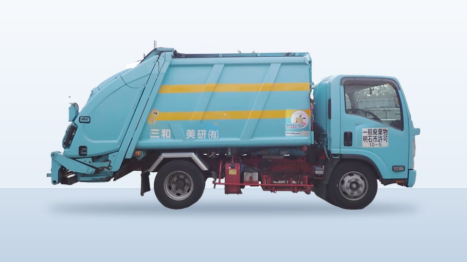 大型のパッカー車の側面。水色の車体に黄色の帯が入っている。